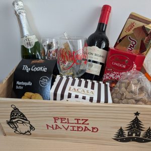 Caja de regalo premium con copas personalizadas, vino, cava y dulces en una caja de madera decorativa.