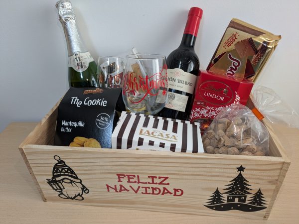 Caja de regalo premium con copas personalizadas, vino, cava y dulces en una caja de madera decorativa.