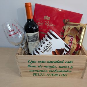aja de regalo navideña con copa personalizada, vino, bombones y dulces en caja de madera con mensaje.