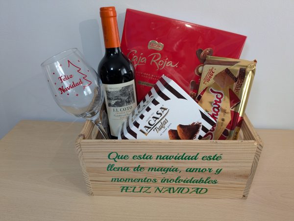 aja de regalo navideña con copa personalizada, vino, bombones y dulces en caja de madera con mensaje.